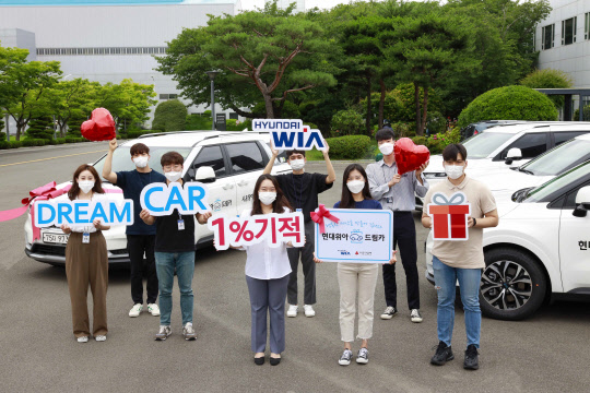 현대위아 직원들이 22일 경상남도 창원시 성산구 현대위아 본사에서 지역 복지기관에 선물할 '현대위아 드림카'와 기념사진을 찍고 있다. <현대위아 제공>